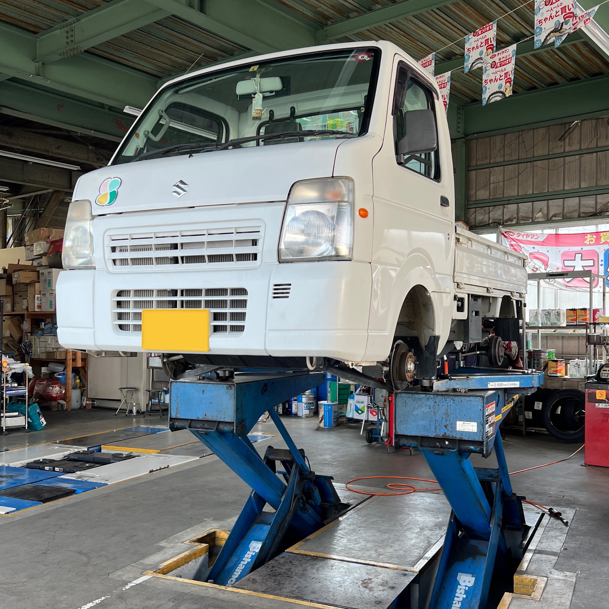 Suzuki Carry kei truck being serviced in a Japanese workshop